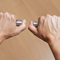 Two hands holding a metallic bar against a beige background