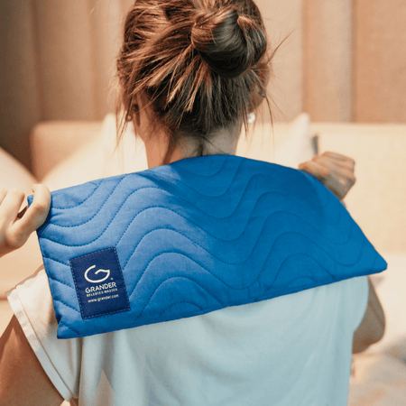 Person using a blue neck pillow with a visible brand logo on a blurred indoor background