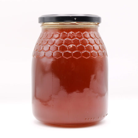 Jar of honey with a honeycomb design on a white background