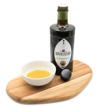 Bottle of Rosmaninho olive oil with a small bowl of oil on a wooden board against a white background
