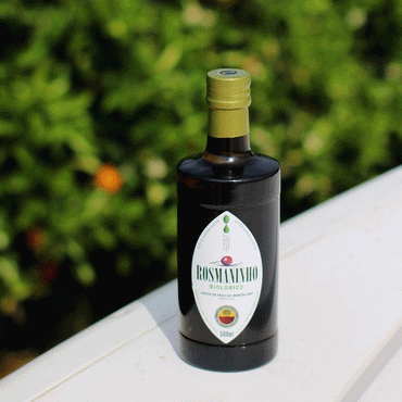 Bottle of Rosmaninho olive oil on a white surface with a blurred green background