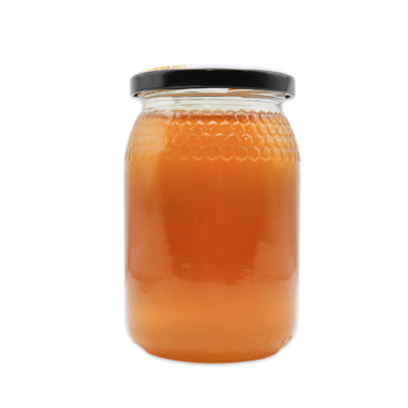Jar of honey with a black lid on a white background
