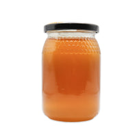 Jar of honey with a black lid on a white background