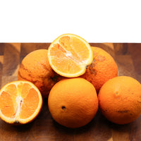 Oranges on a wooden surface with one sliced open